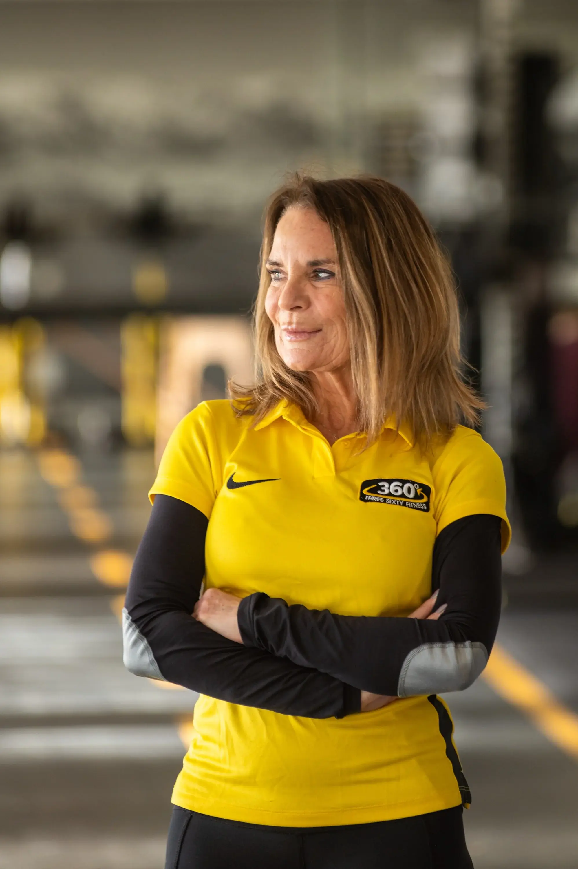 A personal trainer in a yellow Three Sixty Fitness polo shirt